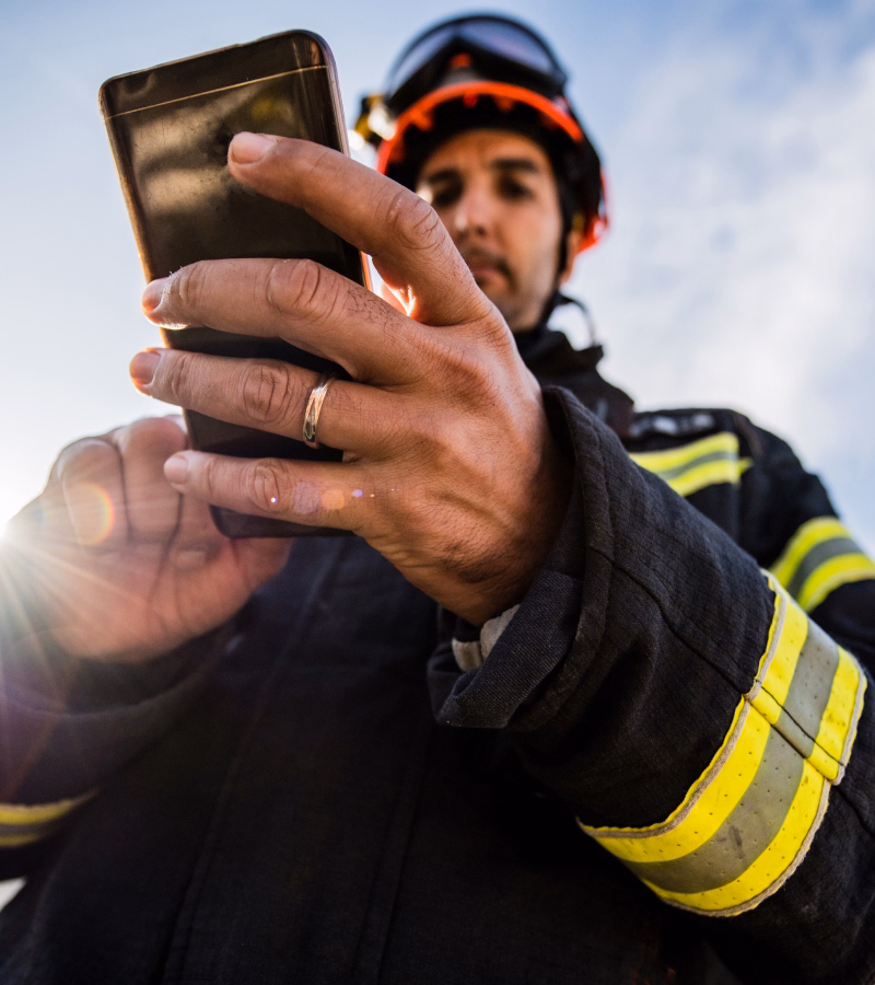 Firefighter in uniform using a smartphone in the field
