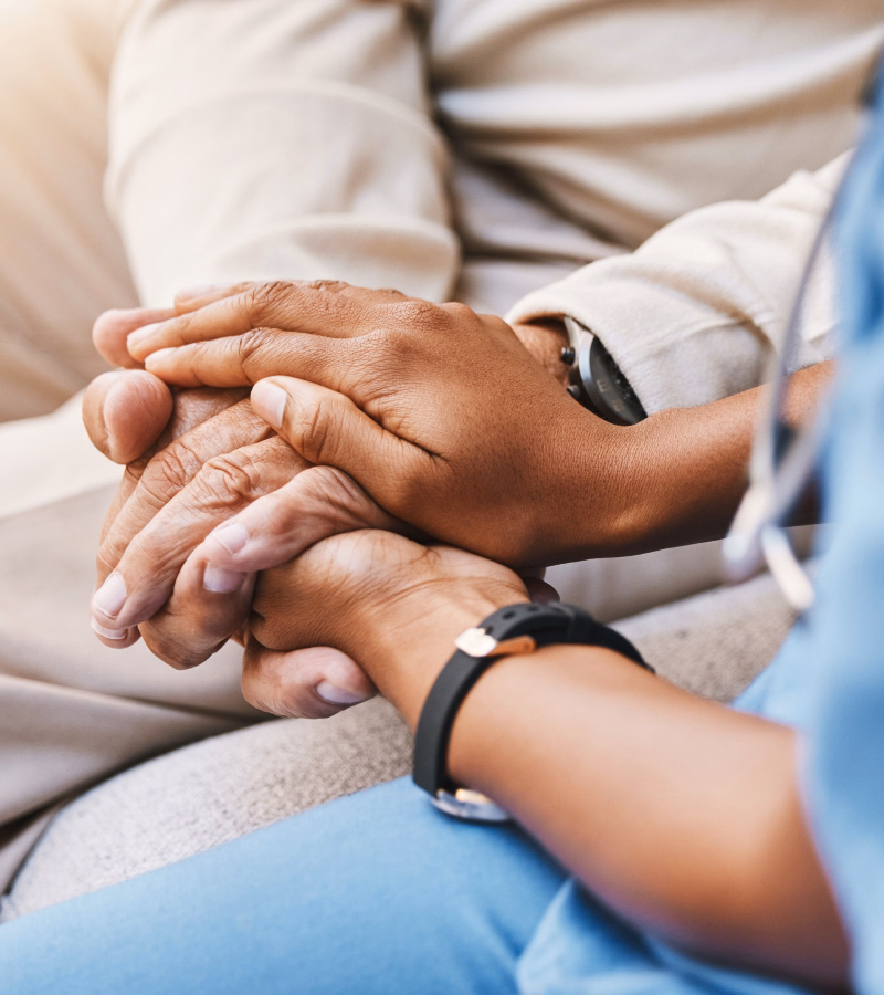 Caregiver holding the hands of an elderly home health patient