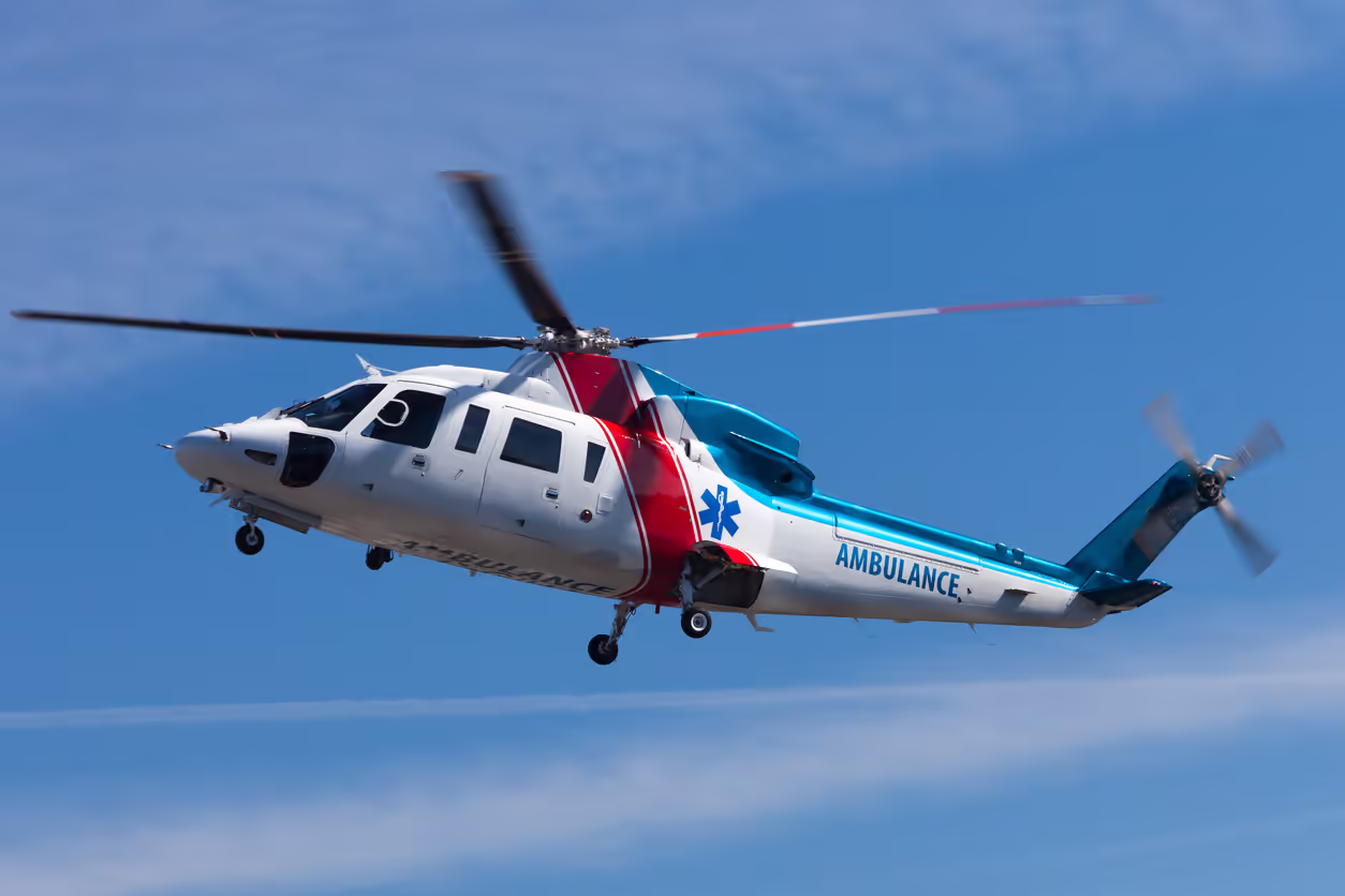 Medical helicopter landing on a hospital rooftop helipad at dusk