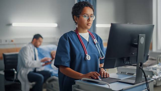 Clinician using an EHR system on a desktop monitor at a hospital workstation